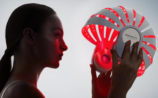 Mujer sosteniendo el casco de luz roja LED de CurrentBody para la salud del cuero cabelludo